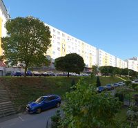 Rozkvet lakótelep Považská Bystricában lakóházakkal és parkoló autókkal.