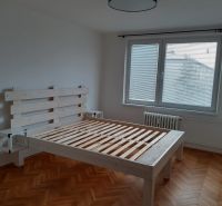 Világos hálószoba fa ággyal és fa dekorációjú padlóval egy kétszobás lakásban.