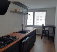 Két szobás lakás konyhája fa mintázatú padlóval és bárasztallal.