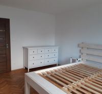Hálószoba fehér bútorokkal és fa dekoros padlóval egy kétszobás lakásban.