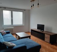 Nappali egy kétszobás lakásban sarokkanapéval és fa mintázatú padlóval.