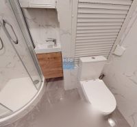 A garzonlakás fürdőszobája zuhanyzót, mosdót és WC-t tartalmaz márványburkolattal.