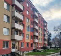 Társasház lépcsőházzal és erkélyekkel, parkolóval az épület előtt, kilátás a garzonlakásra.