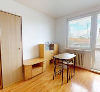 Garzonlakás bútorokkal, asztallal és székekkel, fa dekorációjú padló, nagy ablak redőnyökkel.