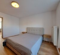 Hálószoba ággyal és éjjeliszekrényekkel, fa dekorációjú padlóval egy kétszobás lakásban.