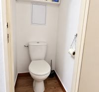 WC polccal és fa dekorációjú padlóval egy háromszobás lakásban.