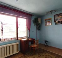 Modra szoba ablakkal, asztallal és székkel egy családi házban.
