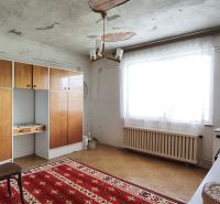 Családi ház belső tere retro bútorokkal, piros szőnyeggel és nagy ablakkal.