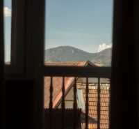Kilátás az ablakból a tetőkre és a hegyekre Liptovský Michalban, szállodák és panziók.