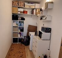 Kompakt szoba polcokkal, szekrénnyel és fa dekorációjú padlóval egy háromszobás lakásban.