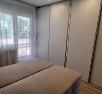 Hálószoba egy háromszobás lakásban nagy gardróbszekrénnyel és függönyös ablakkal.