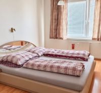 Hálószoba egy háromszobás lakásban, ággyal, tükör alatti szekrénnyel és fa dekoros padlóval.