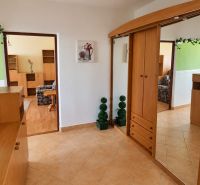 Folyosó egy 3 szobás lakásban fa szekrényekkel és dekorációkkal a bézs csempén.