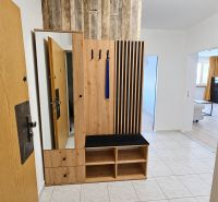 Előszoba fa bútorokkal és csempével egy kétszobás lakásban.