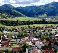 Švošov festői panorámája, amely különféle lakótelkeket ábrázol dombos háttérrel.