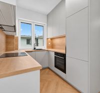 Konyha egy 3 szobás lakásban, fa dekorációjú padlóval és modern készülékekkel.