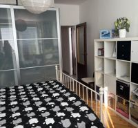 Hálószoba egy kétszobás lakásban tárolóhellyel, ággyal és fa dekoros padlóval.
