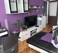 Nappali egy kétszobás lakásban kanapéval és bútorokkal, fa dekoros padlóval.