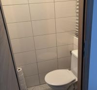 Egyszerű csempével és járólappal burkolt WC egy kétszobás lakásban.