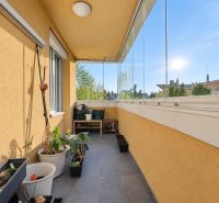 Üvegezett loggia virágládákkal és kilátással a zöldre egy 3 szobás lakásban.