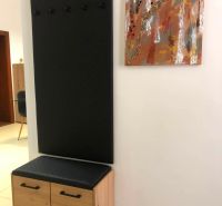 Komód és fogas fekete panellel a kétszobás lakás előszobájában.