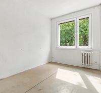 Üres szoba egy kétszobás lakásban nagy ablakkal és radiátorral, világos falakkal.