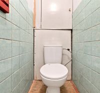 WC zöld csempével a kétszobás lakásban és fa mintázatú padlóval.