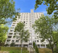 A Hanulova utcai lakóház Dúbravkában, zölddel és kék éggel körülvéve.
