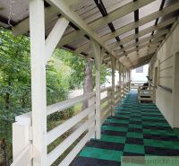 A staškovi családi ház verandája zöld növényzettel és fa dekorációval.