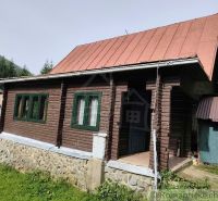 Fából készült házikó bádogtetővel a Rajecká Lesná természetében, zölddel körülvéve.
