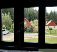 Kilátás a Rajecká Lesná-i házakra, amelyeket zöld növényzet és autók vesznek körül.