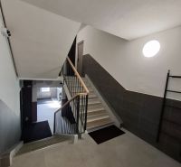 A társasház lépcsőháza egy 3 szobás lakásban modern csempékkel és korláttal.