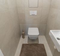 Függesztett WC-vel, kis mosdóval és bézs csempével ellátott WC, Lakásépítés.