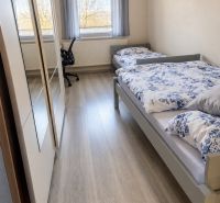 Kétágyas szoba fa mintás padlóval egy családi házban.