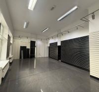 Sötét falakkal és szürke csempével rendelkező üzlethelyiség bérlésre.