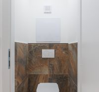 WC barna csempével egy kétszobás lakásban.