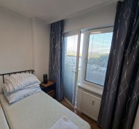 Hálószoba tér egy egyszobás lakásban függönyökkel és kilátással rendelkező ablakkal.