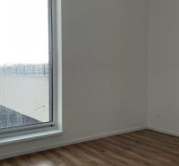 Szoba egy kétszobás lakásban nagy ablakkal és fa dekorációjú padlóval.
