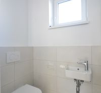 WC mosdóval egy háromszobás lakásban, egyszerű fehér és szürke színséma.