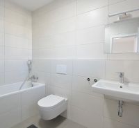 Fürdőszoba egy háromszobás lakásban káddal, WC-vel és mosdóval, bézs színű csempével.