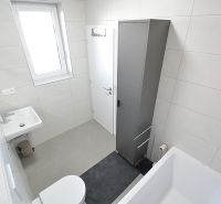 Fürdőszoba egy háromszobás lakásban káddal, mosdóval és szekrénnyel.