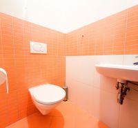 Fürdőszoba egy háromszobás lakásban narancssárga csempékkel és függesztett WC-vel.