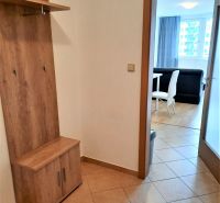 Előszoba egy kétszobás lakásban, akasztós fallal és kilátással a nappalira étkezővel.