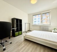 Világos hálószoba egy háromszobás lakásban, ággyal, íróasztallal, polccal és fa dekorációs padlóval.