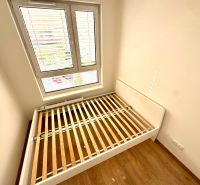 Hálószoba tér fa dekorációs ágykerettel és padlóval egy kétszobás lakásban.