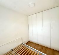 Hálószoba egy kétszobás lakásban fa mintázatú padlóval és nagy szekrénnyel.