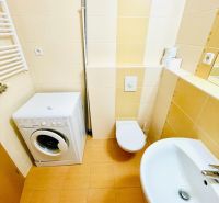 Fürdőszoba egy egyszobás lakásban mosógéppel, mosdóval és WC-vel.