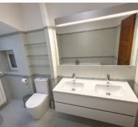 Fürdőszoba családi házban dupla mosdóval, WC-vel és tükörrel.