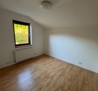 Szoba egy családi házban, fa dekorációjú padlóval és radiátorral az ablak alatt.