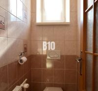 Kis fürdőszoba ablakkal, csempékkel és WC-vel egy családi házban.